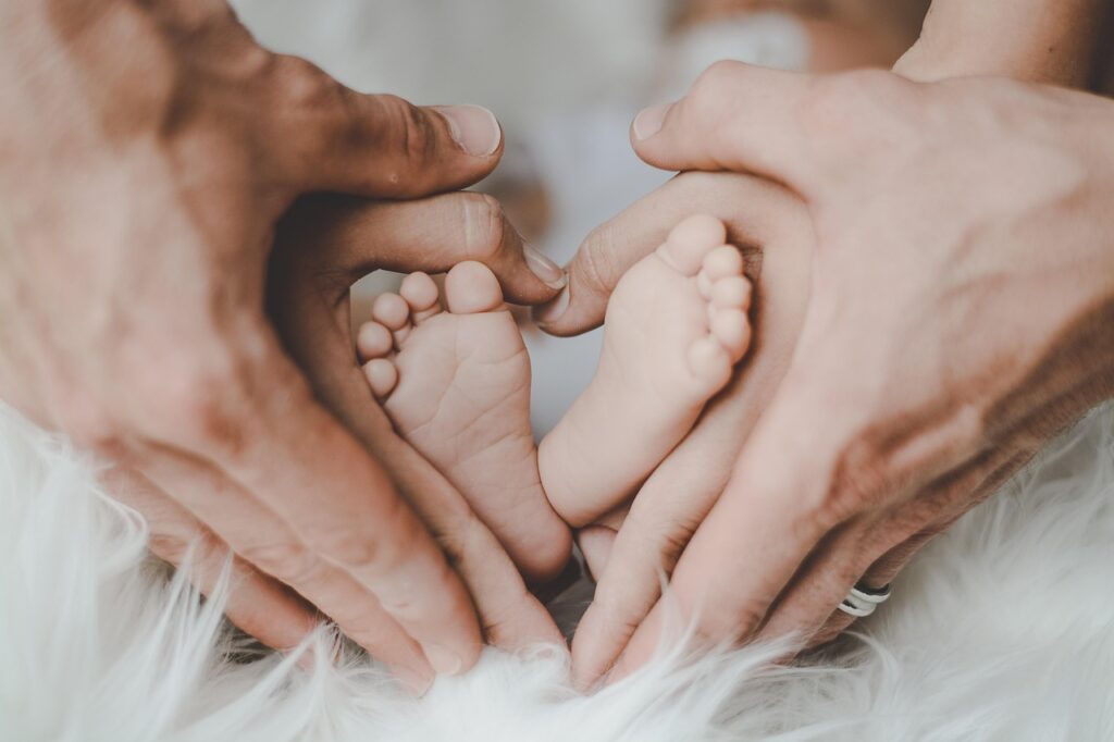 Mains adultes encerclant les pieds d'un nourrisson en forme de coeur